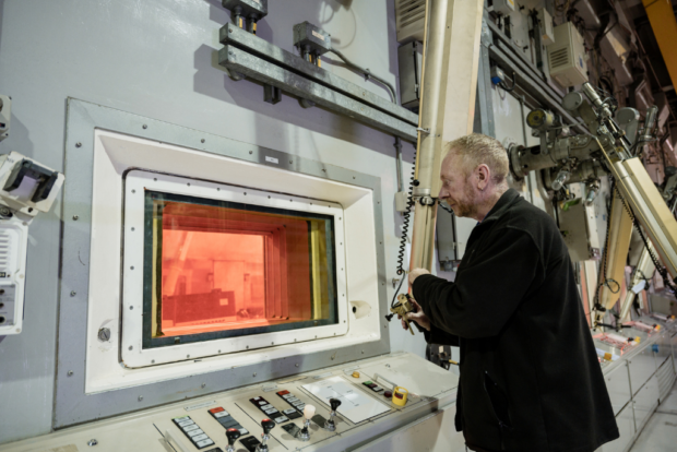 Nuclear operator dismantling AGR fuel using a master slave manipulator in the Fuel Handling Plant on the Sellafield site.