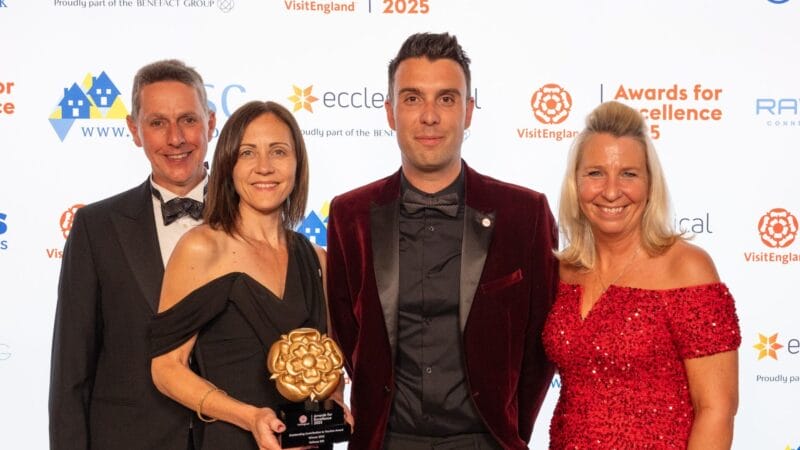 A group of award winners smiling and posing with their trophy on stage at a gala ceremony.