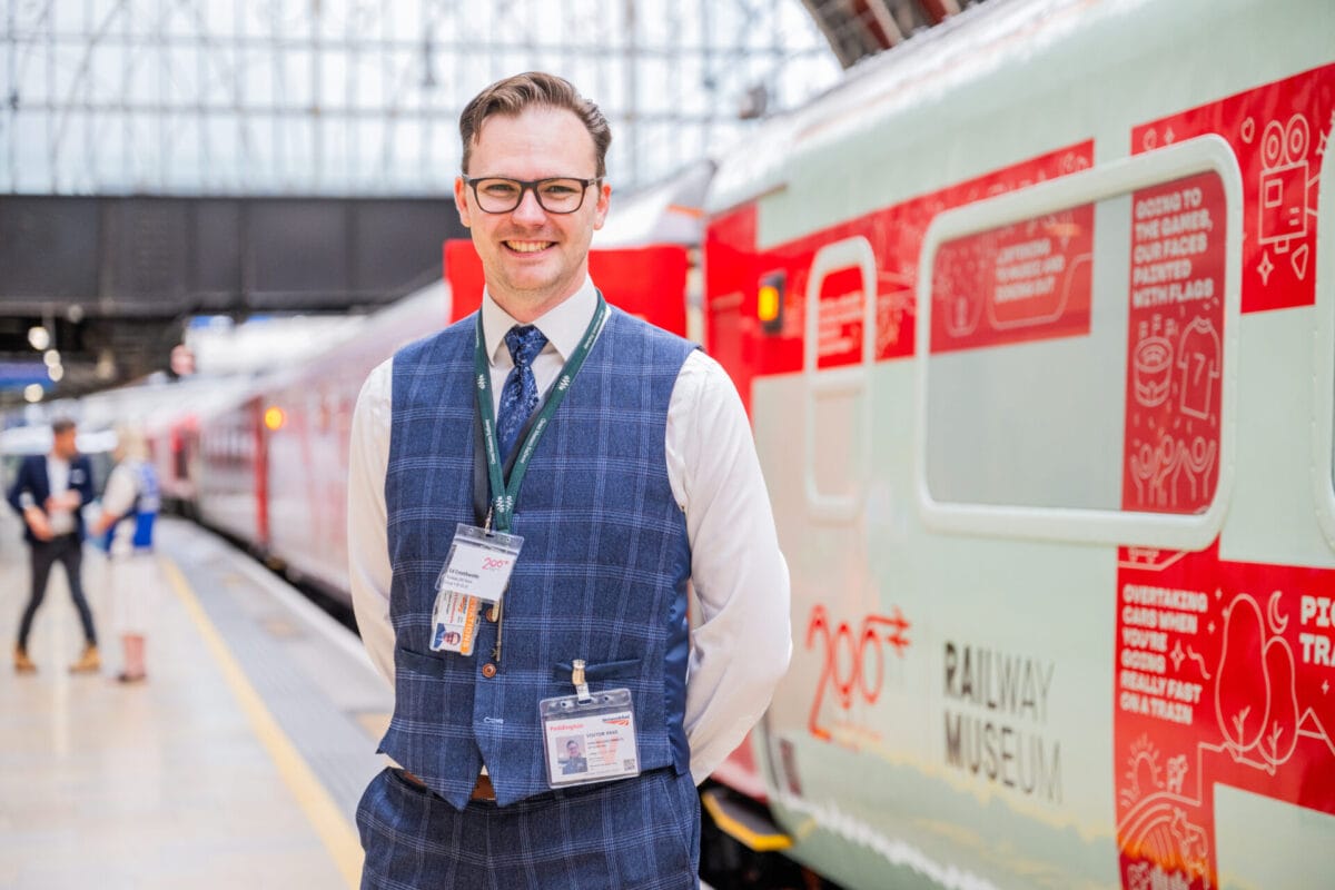A man, smiling, standing in front of a train