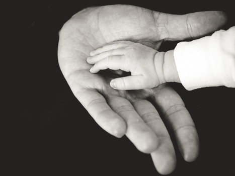 Picture of babys hand compared with adult's hand.