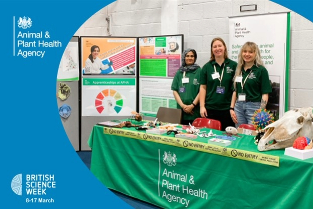 Image of three females in APHA t-shirts at an APHA information stand with the British Science Week logo