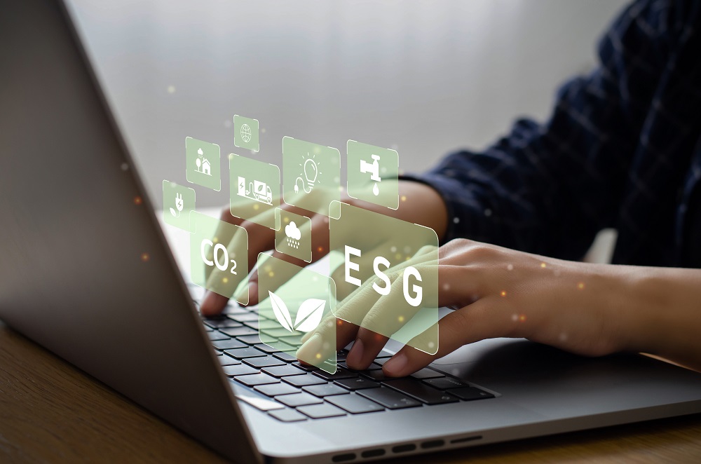 Man's hands seen typing at a laptop. Superimposed over the keyborad area are pale green squares with icons relating to environmental issues (such as a lightbulb, a tap, leaves, a cloud and CO2.)