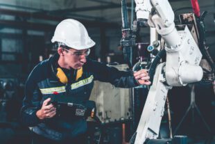 Young factory worker working with adept robotic arm