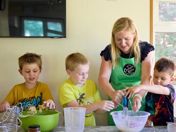Milly and three children mixing ingredients in bowls at a table
