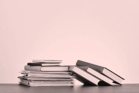 Stack of published advisory committee reports and documents on a desk.