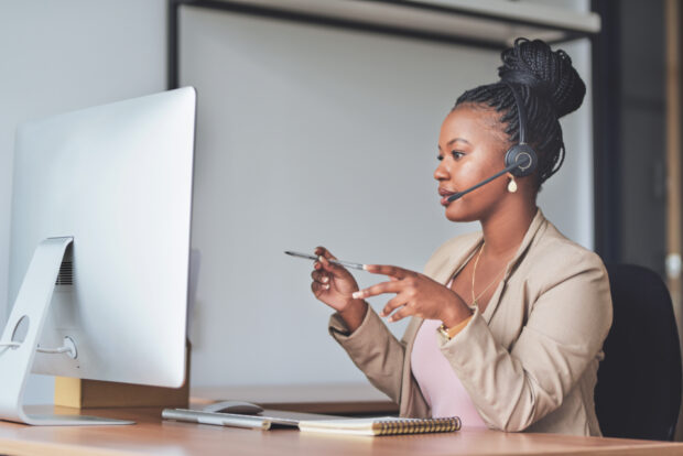 Woman sitting at her desk with a headset on.