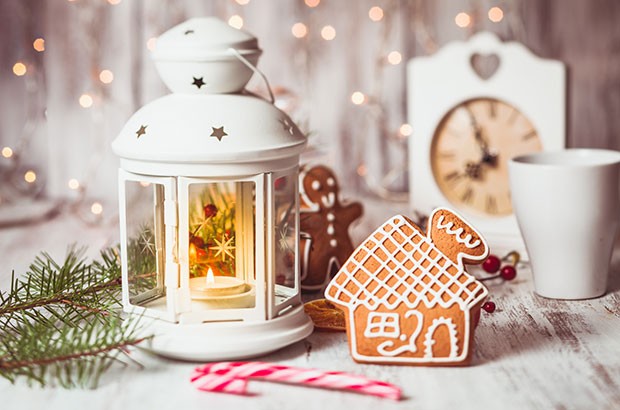 Gingerbread man and house and lantern on a wooden table - festive scene.