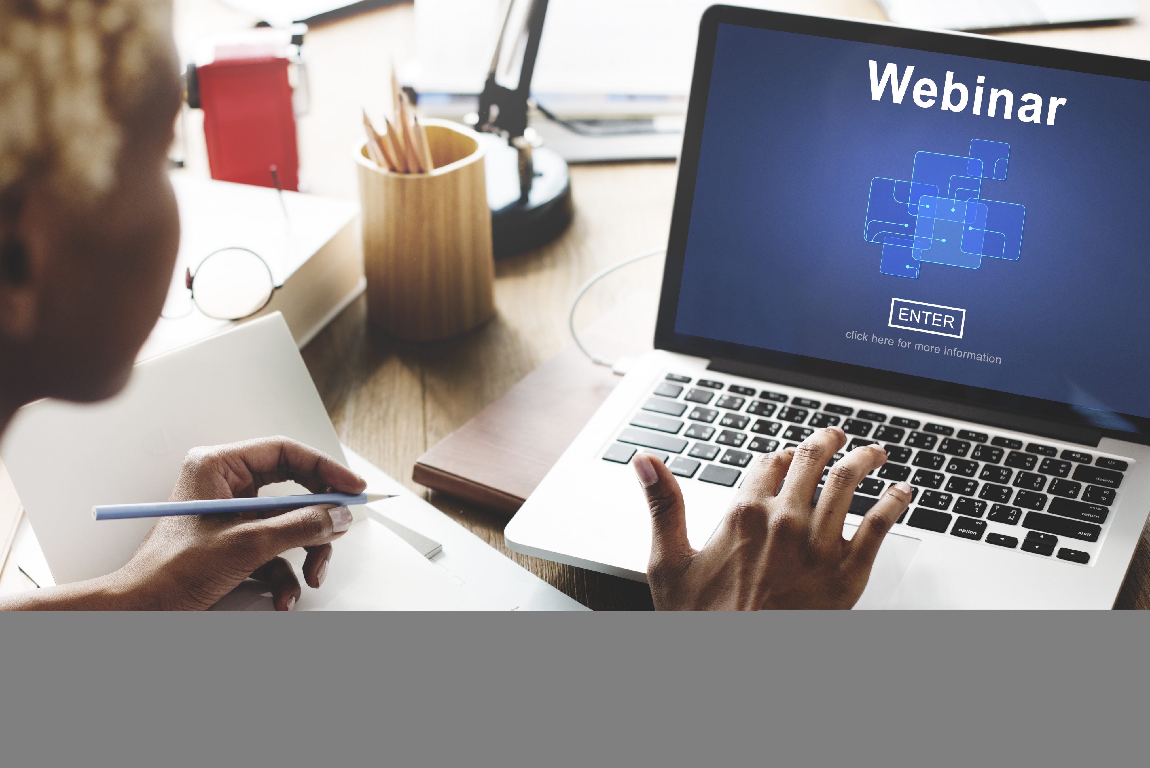 Woman looking at laptop which has the word 'webinar' showing.