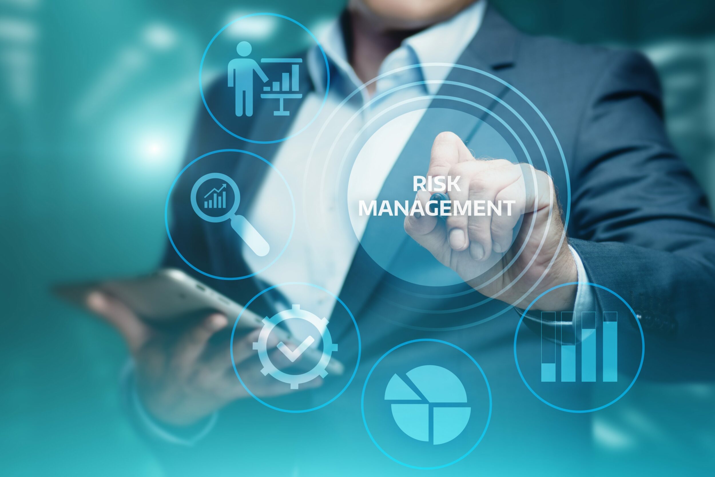 Mid close up of a man wearing a suit, pointing to the words 'risk management'.