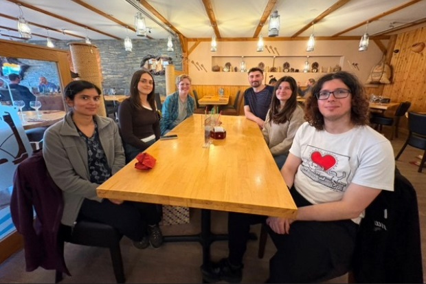 Group photo of six individuals sat around a table.