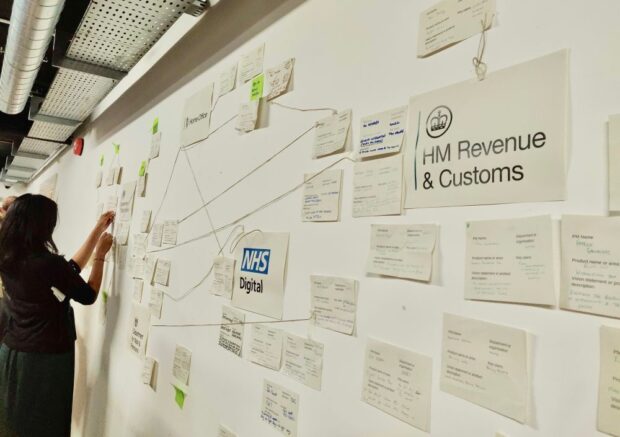 Nasreen working a a wall with papers stuck on it describing government digital services