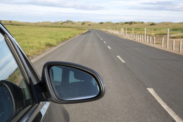 Close up of car's wing mirror as it drives along a quiet road.