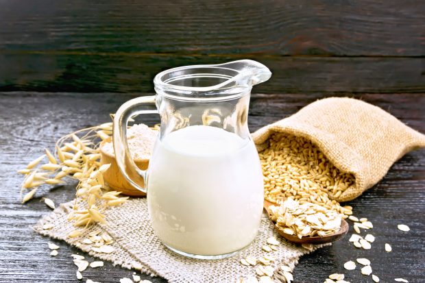 Oat milk in jug with a bag of spilled oats in the background