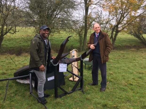 Andrew Sells and a volunteer standing by a beetle sculpture.