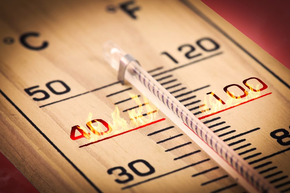 Close up of a wooden temperature gauge with fire at the 40 Celsius mark.