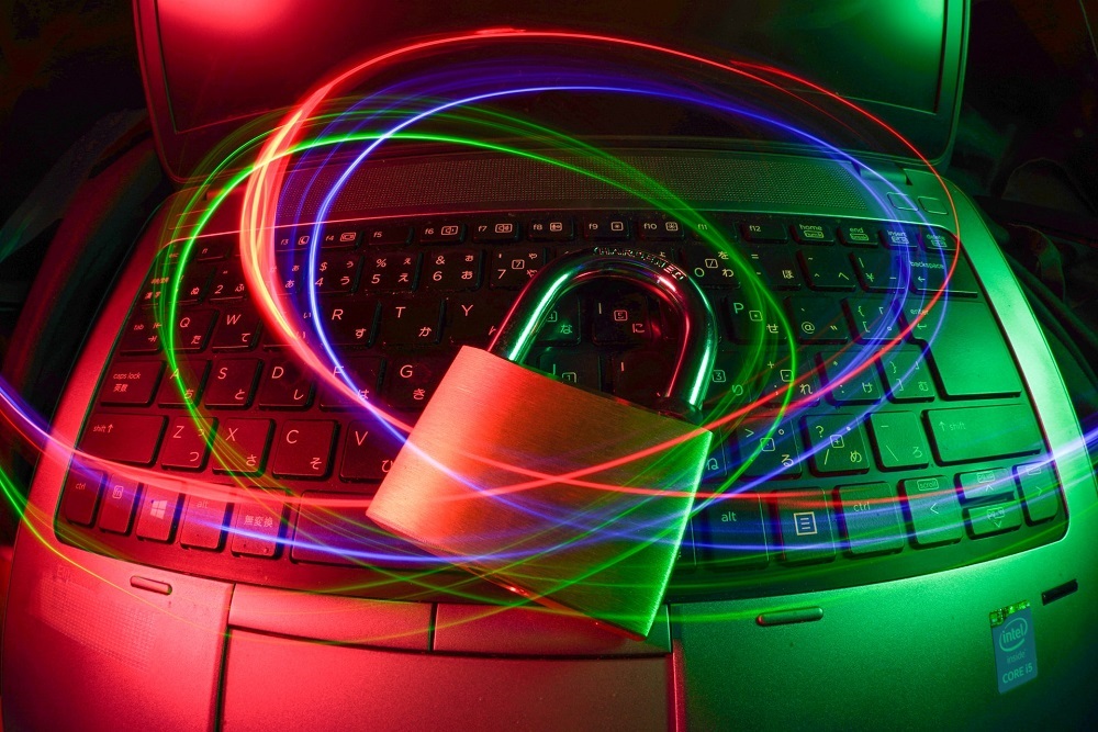 Colours swirl above a laptop and padlock. Credit: Unsplash