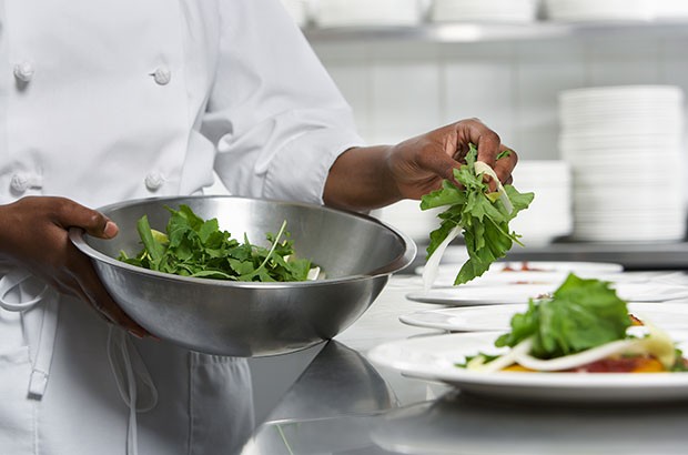 A Chef dressing a dish with a salad.