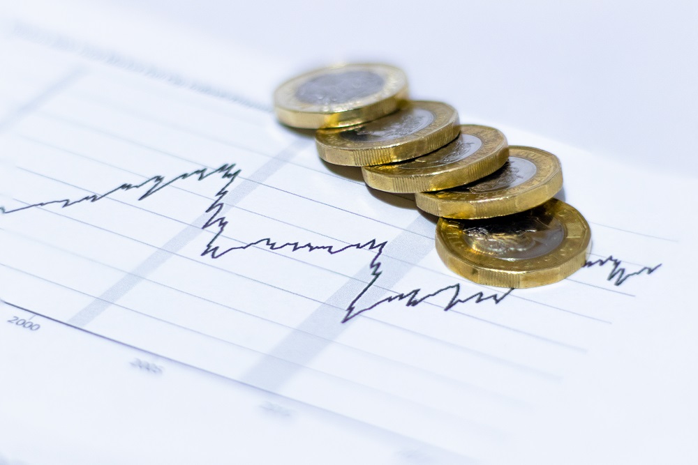 Five one pound coins placed on top of a sheet with a graph