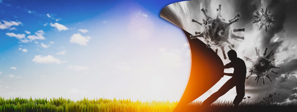 Man in silhouette pulling a curtain across coronavirus molecules. Once the curtain is pulled back the view is of a field in sunshine.