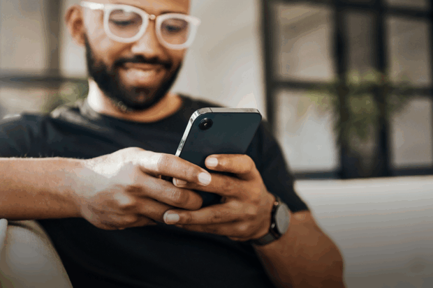 A man smiles whilst looking at his mobile phone