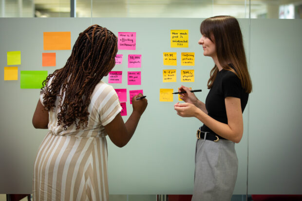 Two women working in a room with post-its on the wall