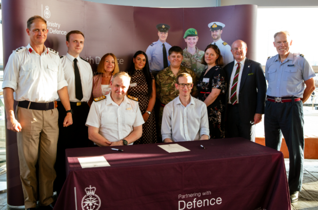 Companies House Chief Executive Andy King signing the Armed Forces Covenant at the Senedd, surrounded by armed forces personnel and Companies House colleagues.