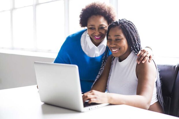 Morther and teenage daughter looking at a laptop.