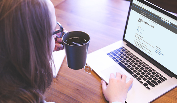 Woman sat in front of laptop with a cup of tea