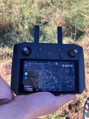 Image shows a close up of a drone remote control, a detailed map of the area can be seen on the display screen