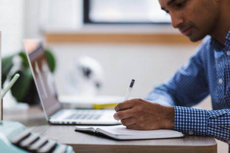 Adult using notepad and looking down at a desk