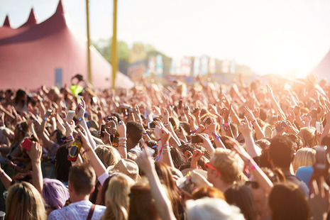 Image shows a crowd of people at an open-air music festival