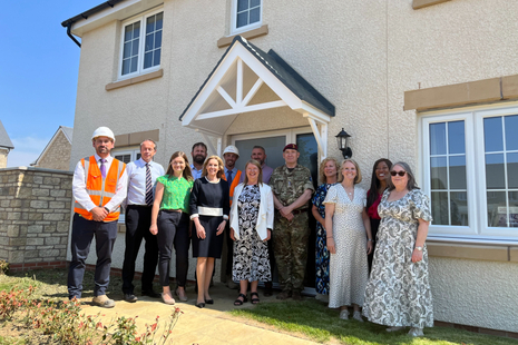 A large group stands in front of a new build house.
