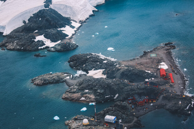 An aerial view of a small island in the antarctic with some buildings visible on it