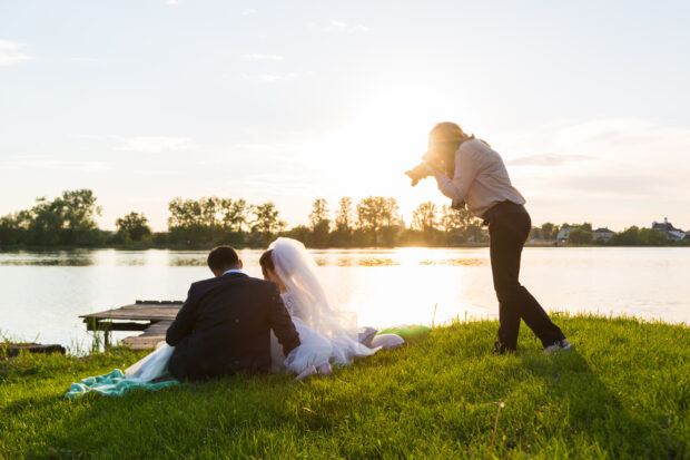 Wedding photographer photographs brides sitting on the lake.