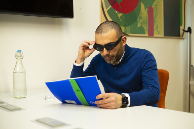 David using his innovative smart glasses to help him read a document.