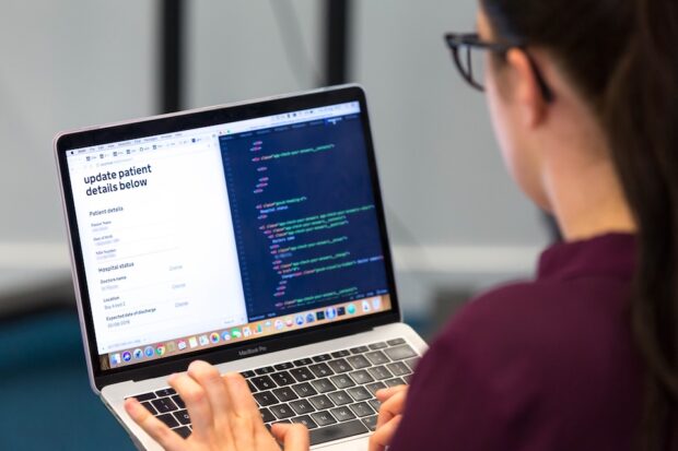 Person with their back to the camera sat in front of a laptop which shows a website open to the left and developer tools open to the right