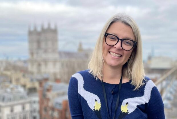 Alt: Portrait of Jen. She is standing outside of an office with Westminster in the background.