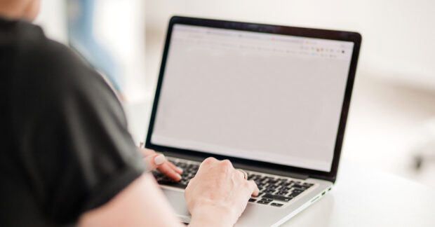 Woman's hands typing on a silver laptop