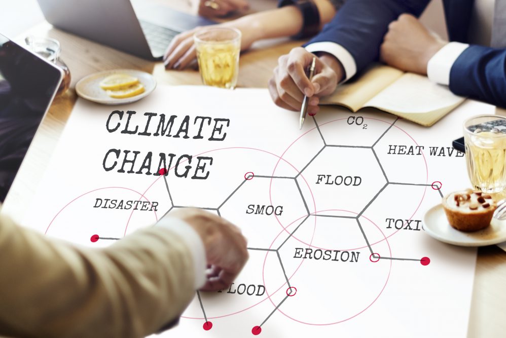 People in a meeting pointing to a large document which has 'climate change' written on it.