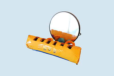 An orange tube with square holes cut into the top next to a round table mirror.