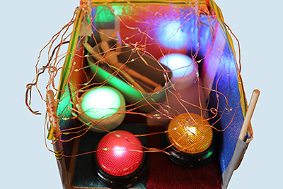A model of a room containing a wooden doll in a bathtub and colourful lights.
