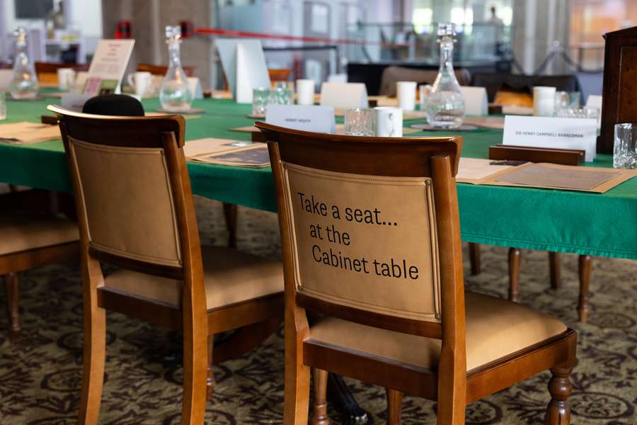 Two chairs. One says "Take a seat at the Cabinet Table" on the back.