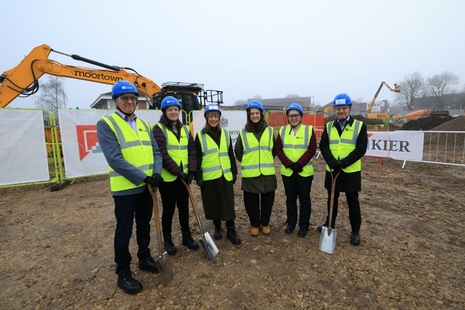 Six people in personal protective equipment standing on a construction site