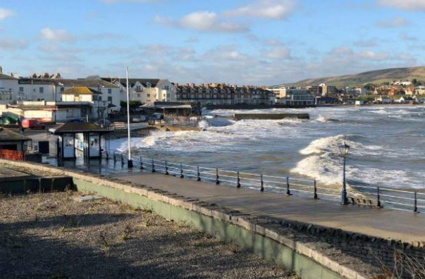 An image of a harbour with waves breaking against the shore.
