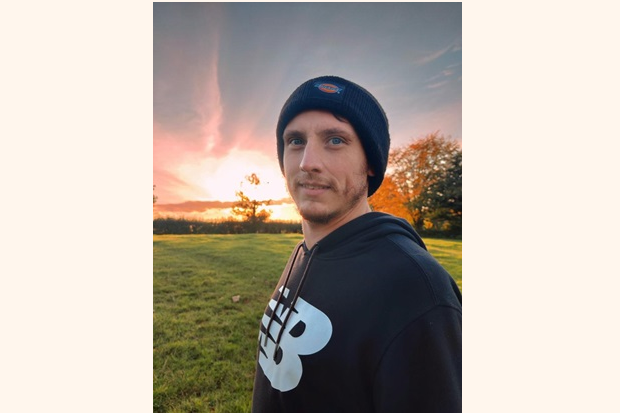 A man wearing a black beanie hat and black sweatshirt.