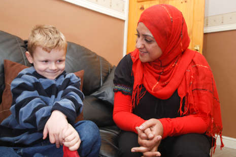 Woman sitting on a sofa looking at a young boy smiling sitting next to her