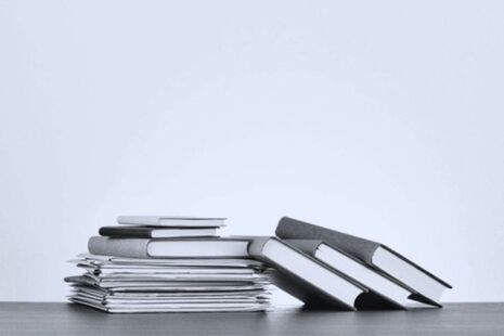 Stack of published advisory committee reports and documents on a desk.