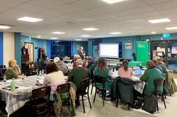 People seated at tables attending an indoor farming and countryside event, listening to a presentation being delivered at the front of the room.