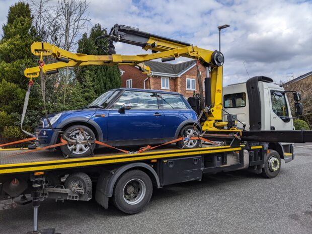 A blue MINI being taken away on a tow truck.