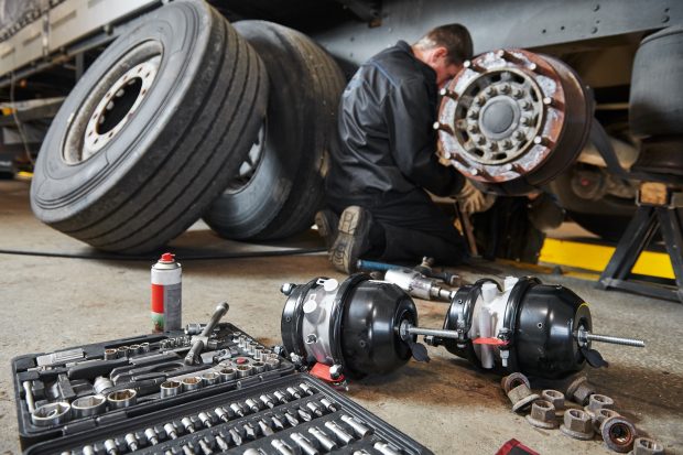 Truck repair service. Mechanic takes off tyre for brake replacement